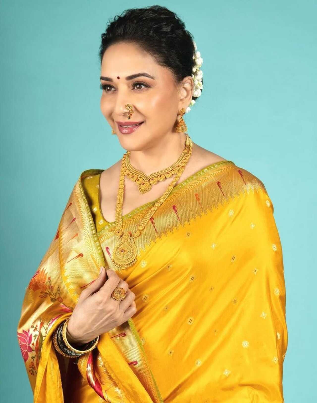 Madhuri Dixit’s vibrant yellow Paithani is a true celebration of tradition. Styled with traditional gold jewellery, a nath, and a neatly tied bun adorned with gajra, her look captures the essence of Maharashtrian culture.